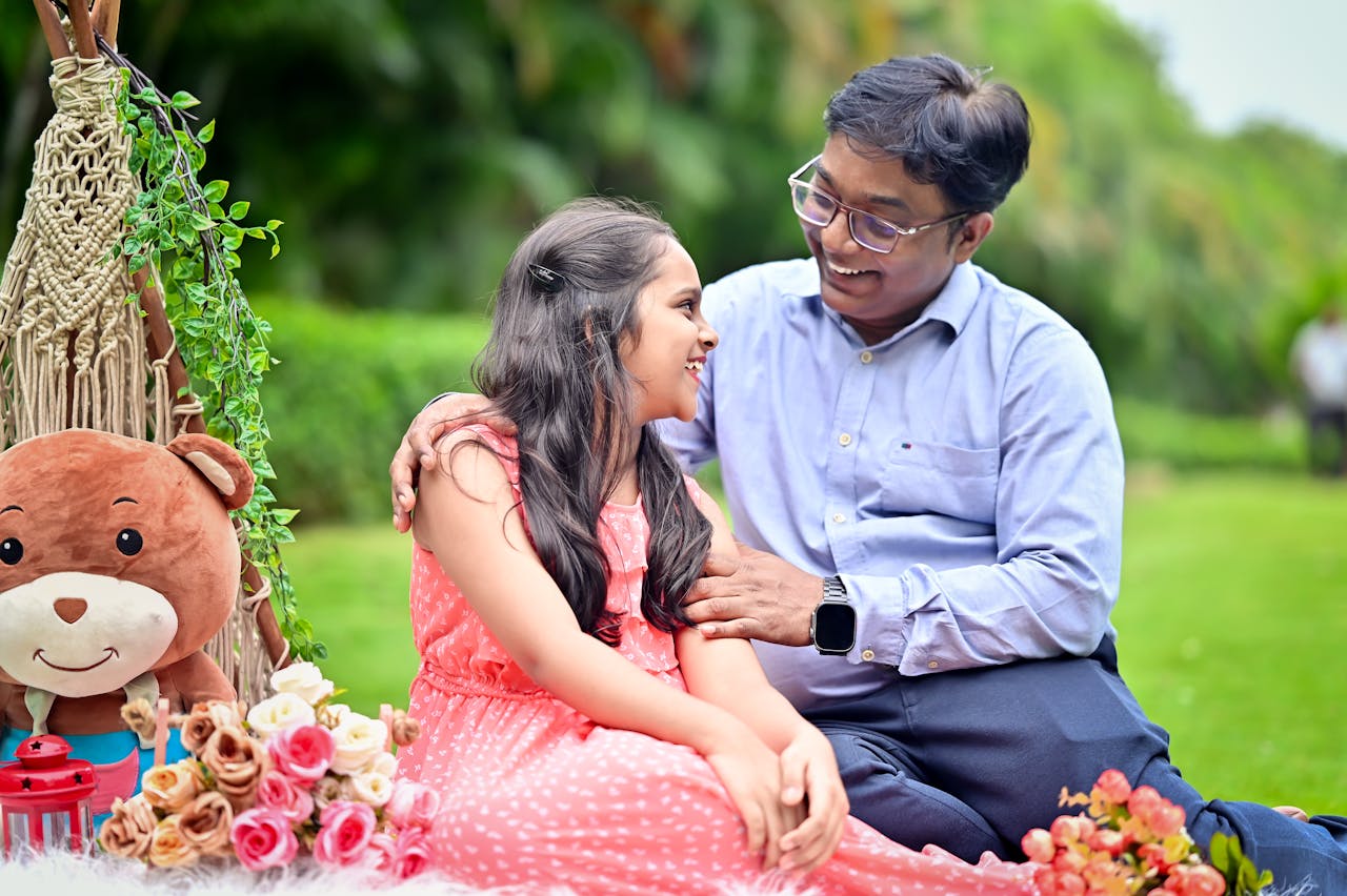 Happy father and daughter bonding during a cheerful outdoor picnic in a garden.