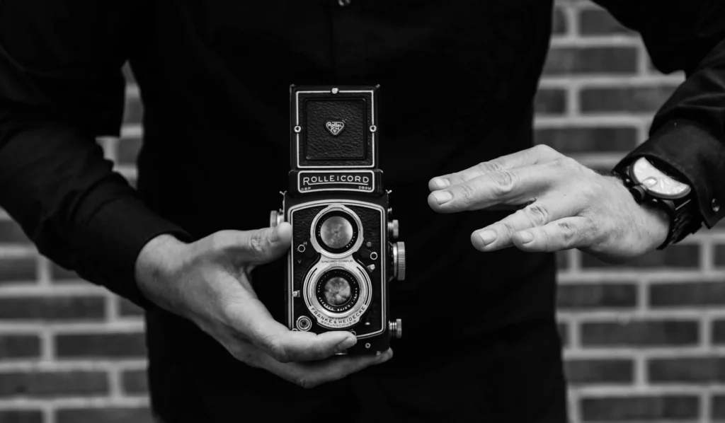 Black and white image of a person holding a vintage Rolleicord camera, emphasizing classic photography.