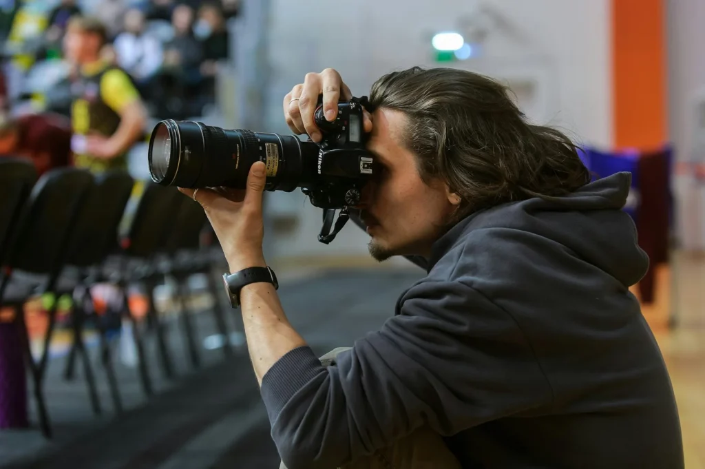 Male photographer capturing moments at an indoor event with a DSLR camera.