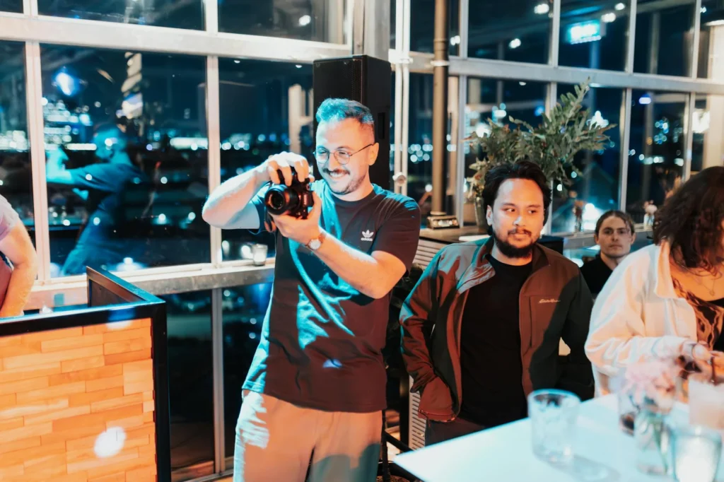 Casual evening team event with a photographer capturing moments indoors.