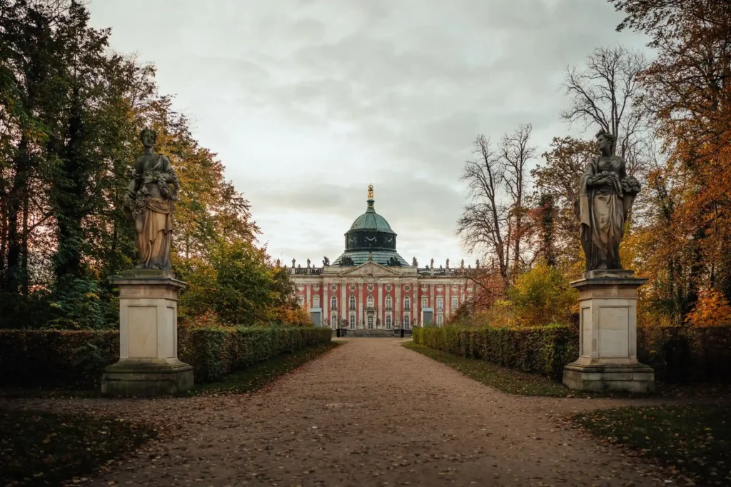 Scenic view of New Palace in Potsdam surrounded by trees and statues during autumn.