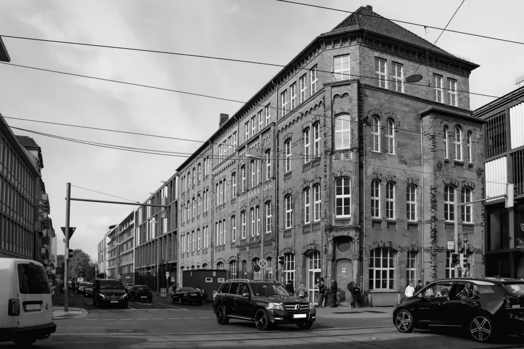 Black and white photo of a historic street corner in Braunschweig, Germany with classic architecture and cars.