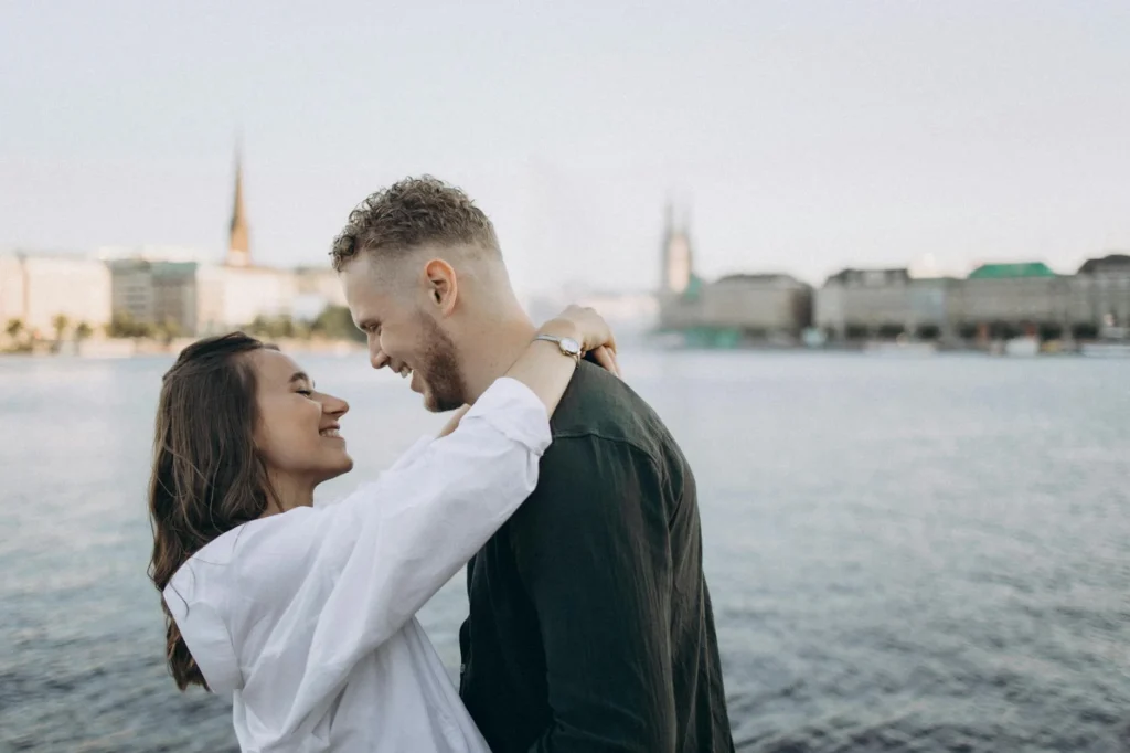 A romantic couple embraces by Alster Lake in Hamburg, Germany during sunset.