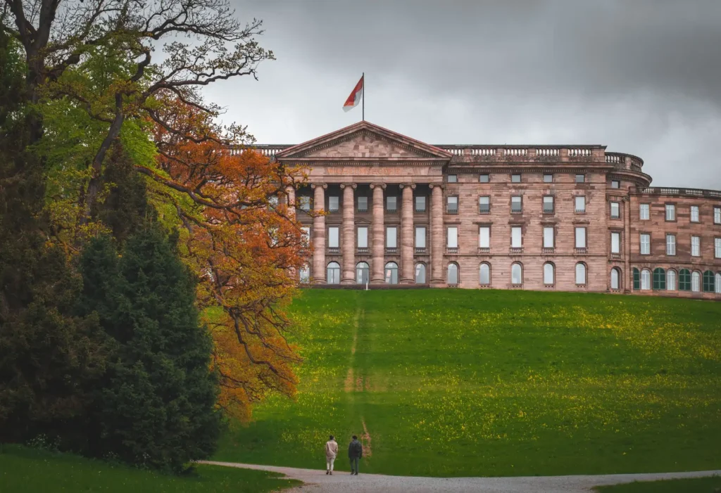 A captivating photo of the iconic Wilhelmshöhe Palace in Kassel, surrounded by lush greenery and autumn colors.