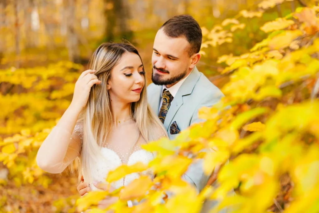 A couple embracing in vibrant autumn foliage, capturing a romantic moment in Brașov's forest.