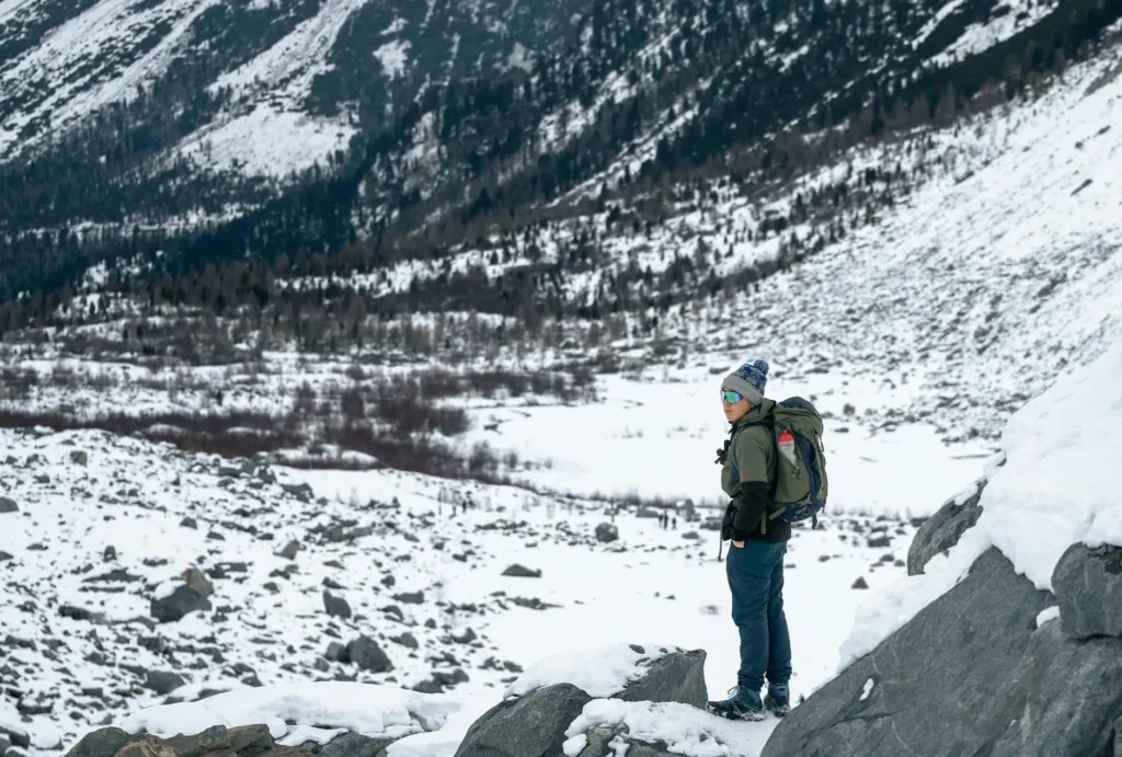 Person hiking in snow-covered mountains with backpack, winter season adventure.