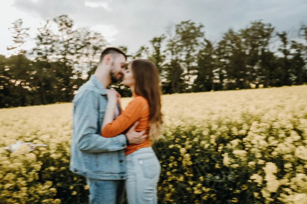 A couple shares an intimate moment in a vibrant yellow field, signifying love and affection.